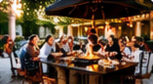 Family gathering around an outdoor hibachi grill on a patio